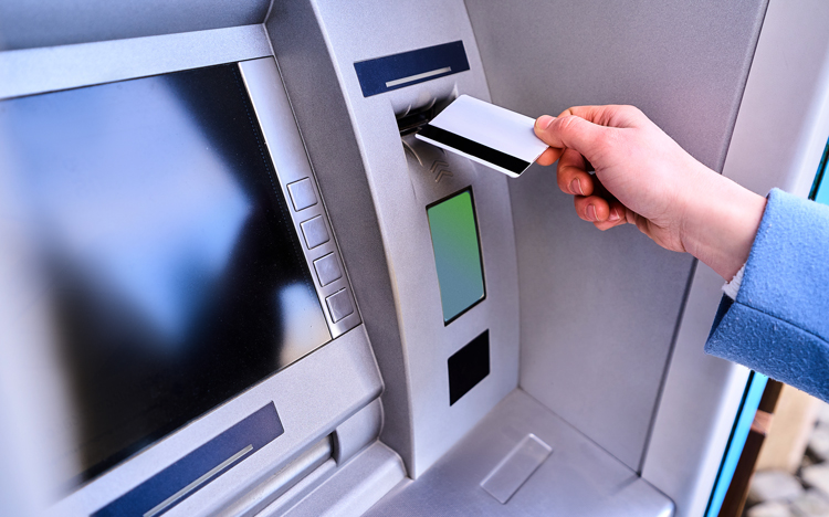 Person using bank card to withdraw money from ATM